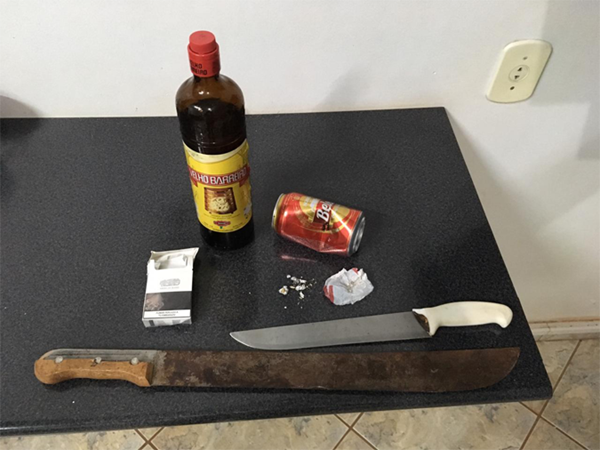 Durante buscas foi encontrada uma faca e um facão. Os policiais também localizaram uma garrafa de pinga, e uma pequena quantidade de crack e cocaína.(Foto: Xeretando)
