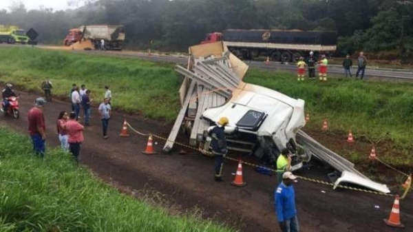 Com a forte batida o caminhão carregado com postes caiu em uma ribanceira, o motorista ficou preso as ferragens e morreu no local. (Foto: PRF)
